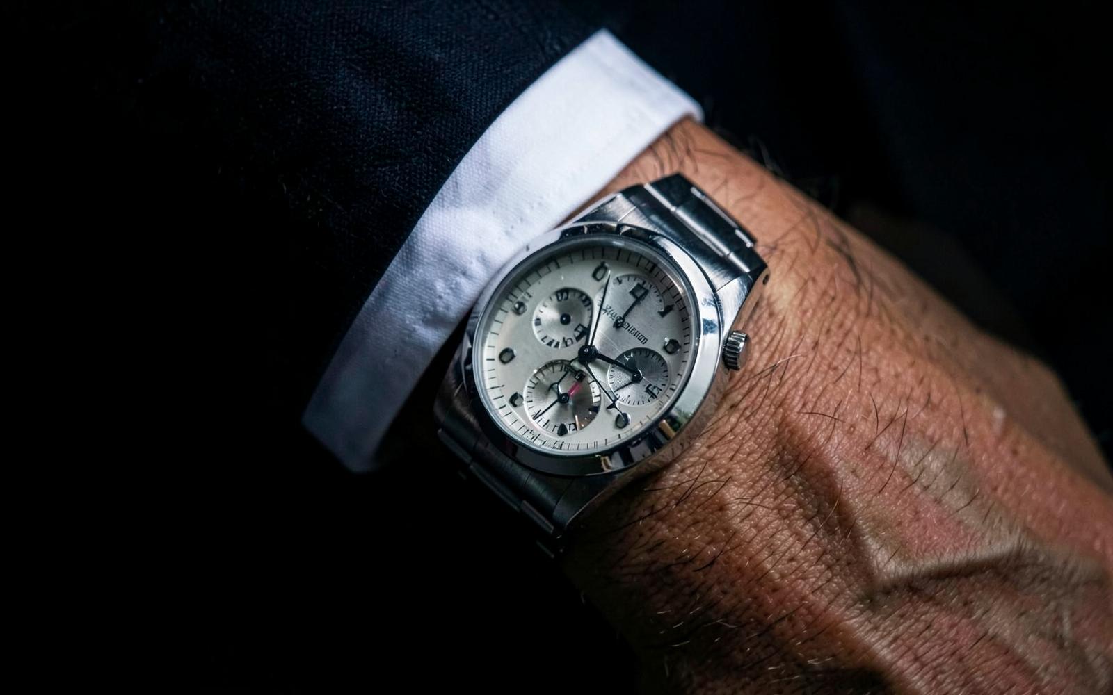 Nahaufnahme des Relieamphi Chronographen R-01 am Handgelenk unter einer Anzugmanschette